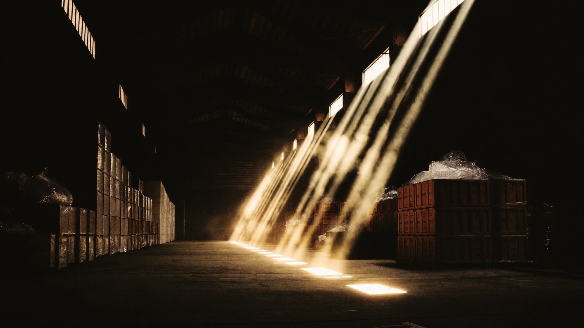 Import warehouse with stacked fabric bales in shafts of light