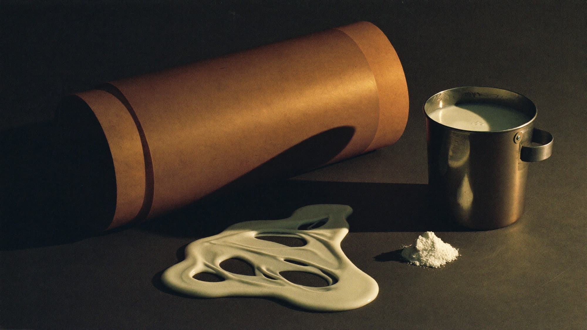 Raw material for artificial leather: a roll of release paper beside a pail of white PVC emulsion and additive powder