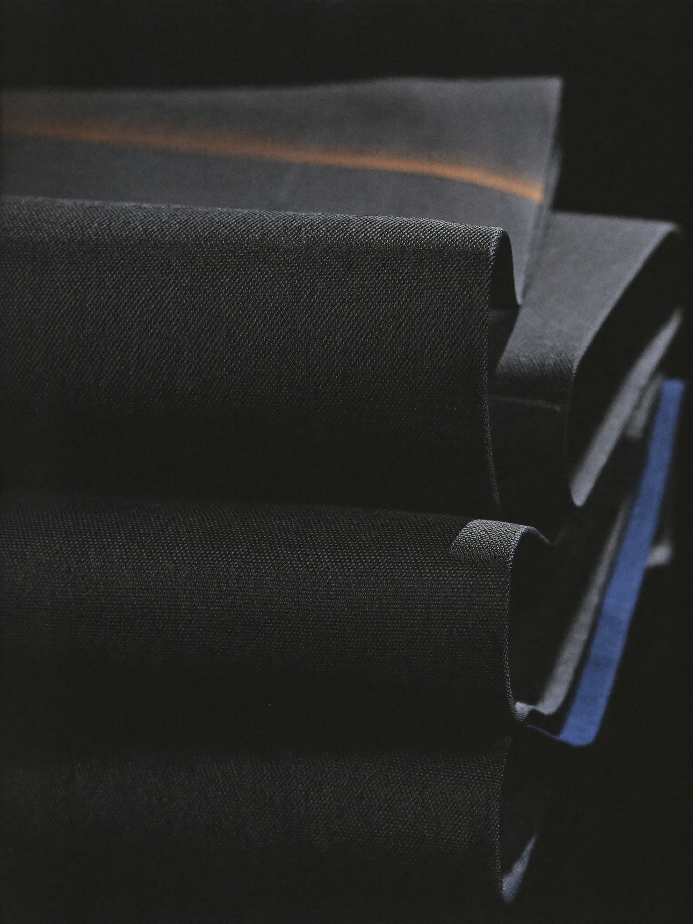 Suiting fabric: folded stacks of charcoal and navy suiting cloth